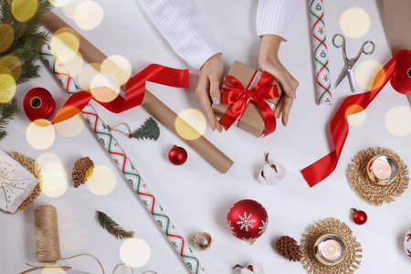 Woman wrapping Christmas gift at white table, top viewの写真素材