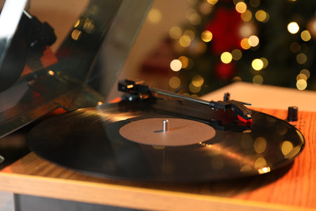 Turntable with vinyl record on table near Christmas tree, closeupの写真素材