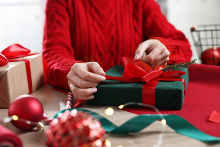 Woman wrapping Christmas gift at wooden table, closeupの写真素材