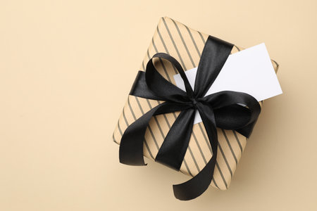 Beautiful wrapped gift with blank card on beige background, top viewの写真素材