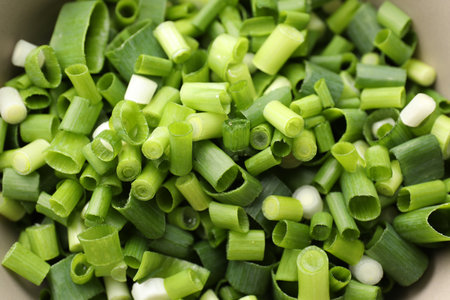 Cut green onions in bowl, closeup view