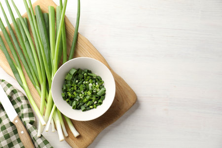 Fresh ripe green onions and knife on white wooden table, top view. Space for textの写真素材