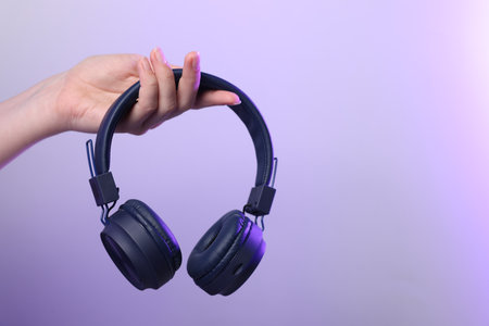 Woman with stylish headphones on violet gradient background, closeup. Space for textの写真素材