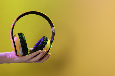 Woman with stylish headphones on yellow background, closeup.