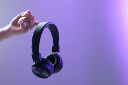 Woman with stylish headphones on violet gradient background, closeup.の写真素材
