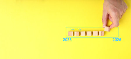 Man putting wooden cube next to others onto loading bar on yellow background, top viewの写真素材