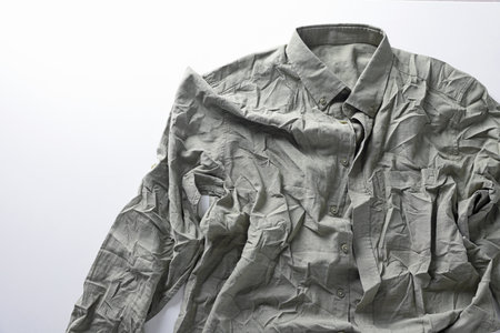 Green creased shirt on light background, top view