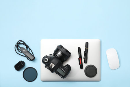 Professional photographer's equipment on light blue background, flat lay. Space for text