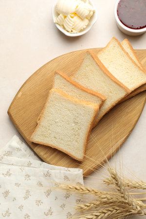 Slices of toast bread, butter and jam on beige table, flat lay