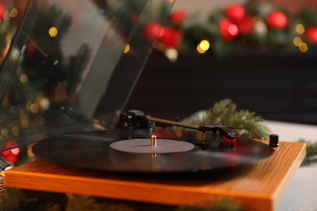 Turntable with vinyl record on table in room decorated for Christmas, closeup
