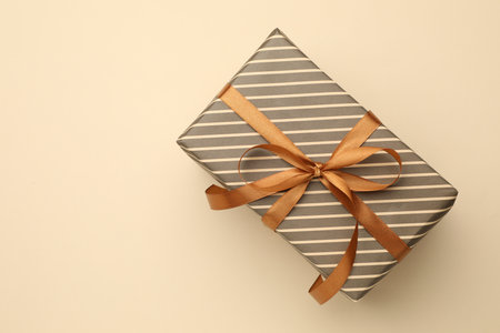Beautiful wrapped gift on beige background, top view. Space for textの写真素材