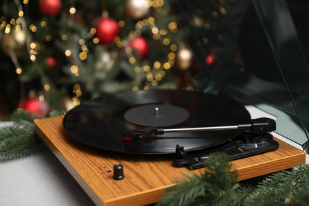 Turntable with vinyl record on table near Christmas tree, closeupの写真素材
