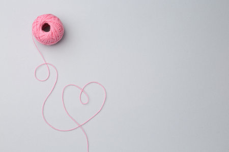 Ball of pink yarn on white background, top view. Space for text