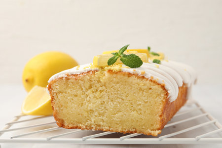 Delicious lemon cake with glaze, fresh fruit slices and mint on light table, closeup