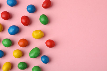 Delicious colorful candies on pink background, flat lay. Space for text