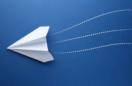 Paper plane with dotted lines as air route track on blue background