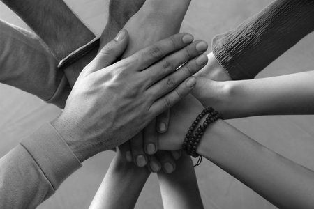 Group of people stacking their hands together, top view. Black-and-white toningの写真素材