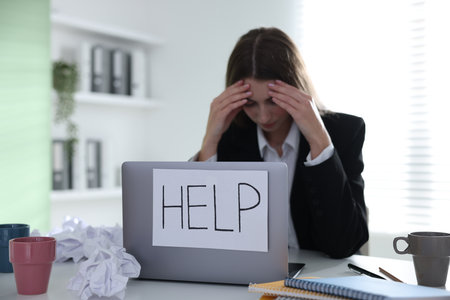 Woman with sign Help on laptop at table in office, selective focus