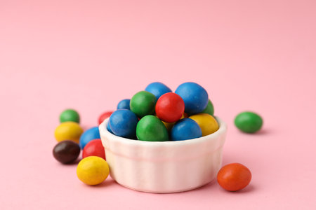 Delicious colorful candies in bowl on pink background, closeup. Space for text