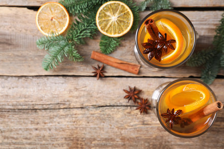 Delicious mulled white wine with slices of orange, spices and fir branches on wooden table, flat lay. Space for textの写真素材