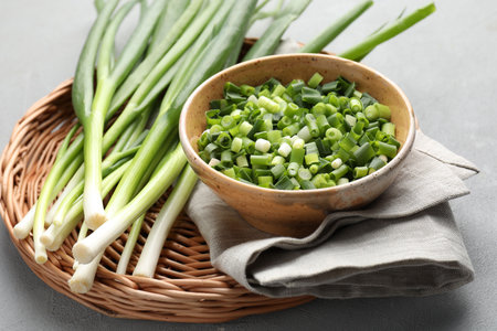Whole and cut fresh green onions on gray table, closeupの写真素材