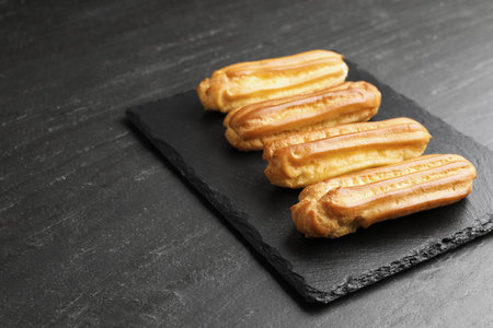 Tasty eclairs on black table. Space for text