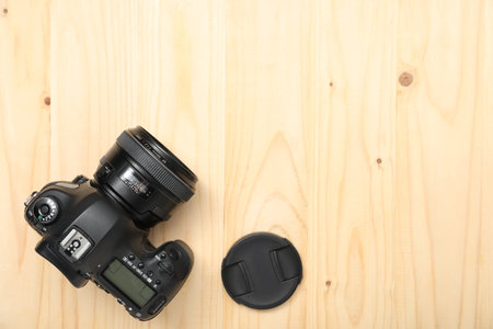 Professional camera and lens cover on wooden background, top view with space for text....