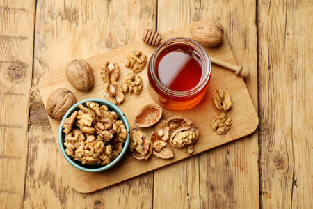 Honey in glass jar, dipper and walnuts on wooden table, top viewの写真素材