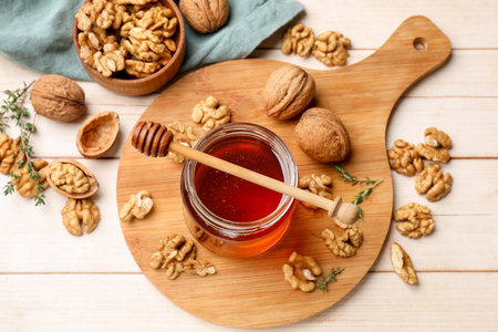 Sweet honey with walnuts, thyme and dipper on wooden table, flat layの写真素材