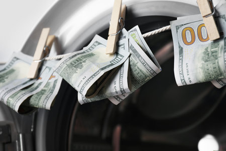 Banknotes hanging on clothesline near washing machine, closeupの写真素材