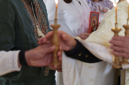 Mykolaiv, Ukraine - November 1, 2025: Priest giving burning candles to people during ceremony,...