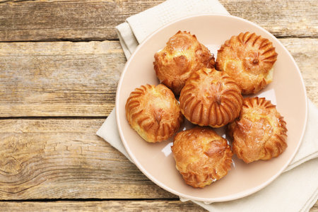 Tasty profiteroles on wooden table, top view. Space for text