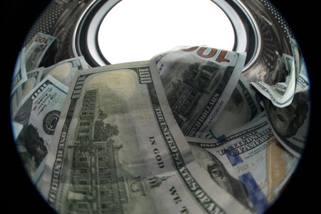 Many dollar banknotes in washing machine against white background, view from inside drum. Wide angle lensの写真素材