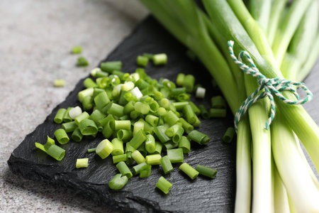 Fresh ripe green onions on light gray table, closeup