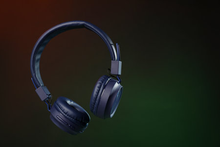 Pair of stylish headphones in air on dark background, space for text