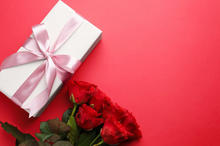 Beautiful gift and roses on red background, flat lay with space for text. Saint Valentine's dayの写真素材