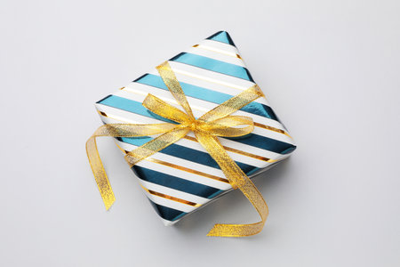 Beautiful wrapped gift on light background, top view