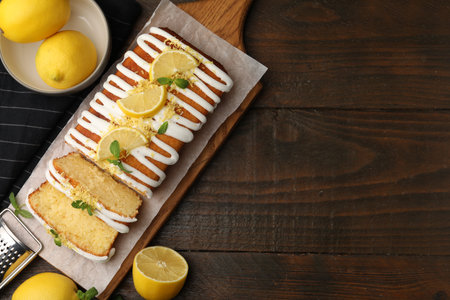Delicious lemon cake and fresh citrus fruits on wooden table, flat lay. Space for textの写真素材