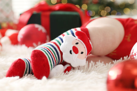 Baby in Christmas socks and festive decor on bed, closeupの写真素材