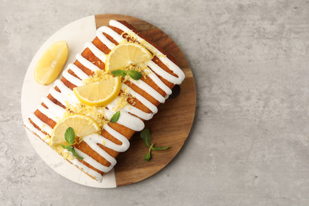 Lemon cake with glaze, fruit slices and mint on gray textured table, top view. Space for textの写真素材
