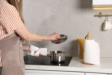 Woman using paper towel while cooking in kitchen, closeup