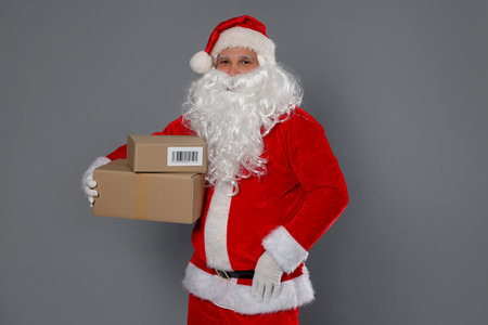 Santa Claus with parcels on gray background