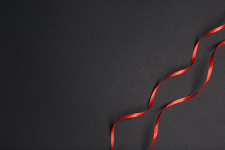 Beautiful red ribbons on dark background, top view. Space for textの写真素材