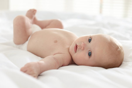 Cute newborn baby in diaper on bed indoorsの写真素材