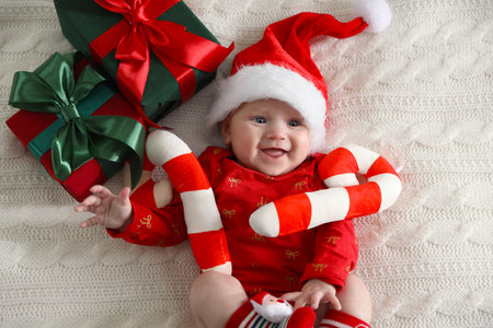 Baby in Santa hat and Christmas decor on bed, top view