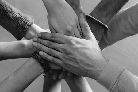 Group of people stacking their hands together, top view. Black-and-white toningの写真素材