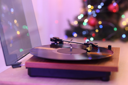 Turntable with vinyl record and Christmas tree on wooden tableの写真素材