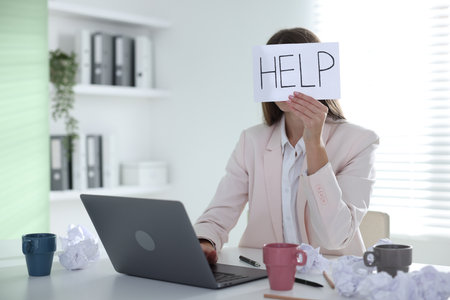 Woman with laptop and sign Help at table in officeの写真素材