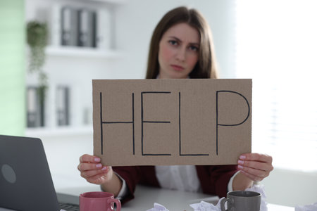 Woman with laptop and sign Help at table in office, selective focusの写真素材