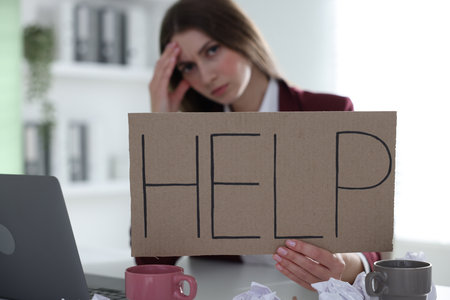 Woman with laptop and sign Help at table in office, selective focus